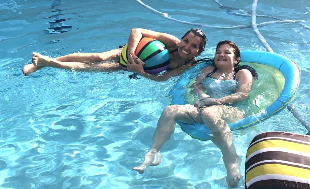 Coach Dana floating in the pool with a student during a private lesson.